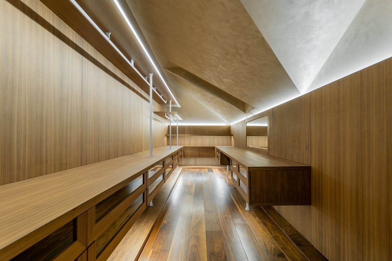 gallery-6 Spacious contemporary walk-in closet with sleek wooden design and ambient lighting.