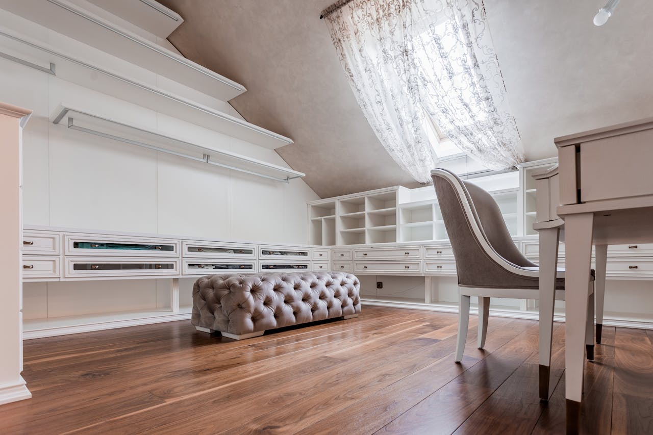 hero-img-01 Stylish attic studio featuring a modern desk, pouffe, and sloping ceiling under natural light.