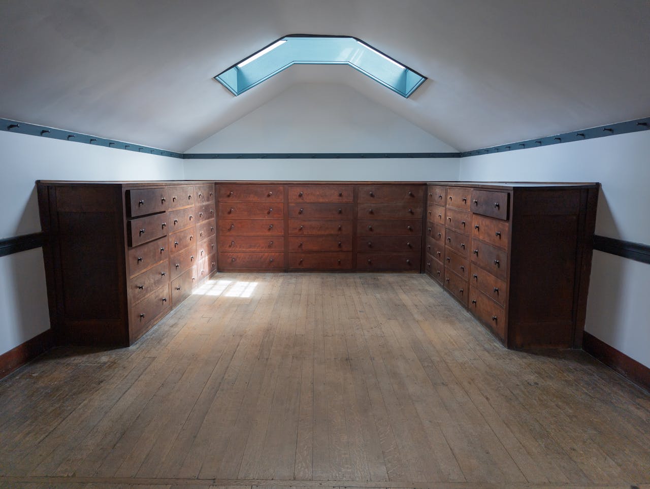 hero-img-02 Shaker-style storage room featuring wooden drawers and a skylight, emanating rustic charm.