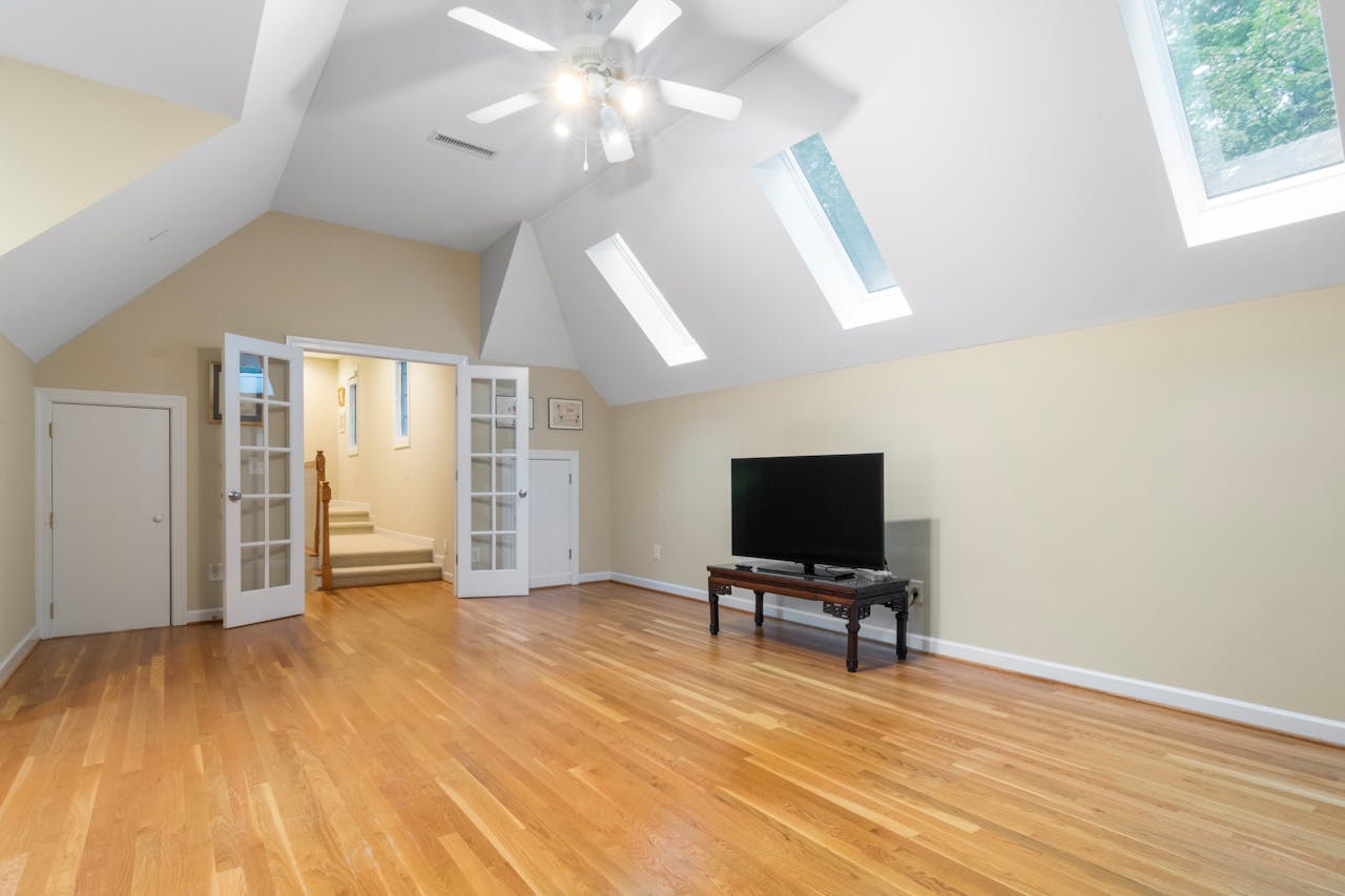 about-01 Bright attic room featuring skylights, wooden floors, and a TV setup, perfect for modern living.